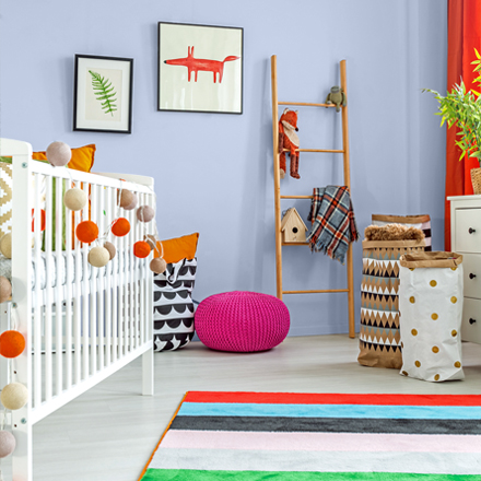 Una colorida habitación para bebés con una cuna y una alfombra de colores.