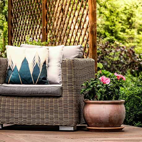 Una silla de mimbre sobre una terraza de madera en un jardín