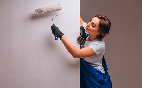 Una mujer pintando una pared con un rodillo.